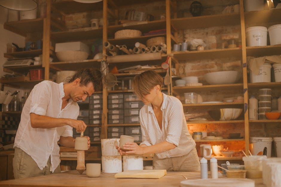 A couple engaged in ceramic art creation in a workshop, surrounded by pottery tools and materials.